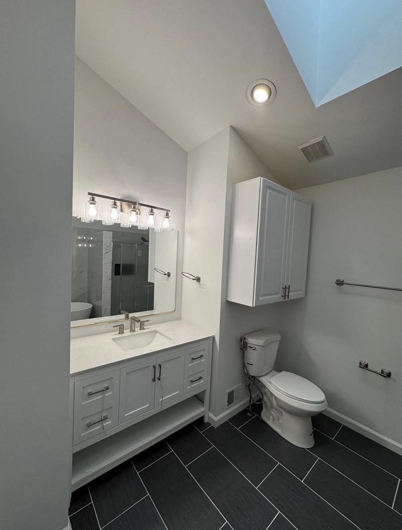White bathroom vanity and dark tile flooring